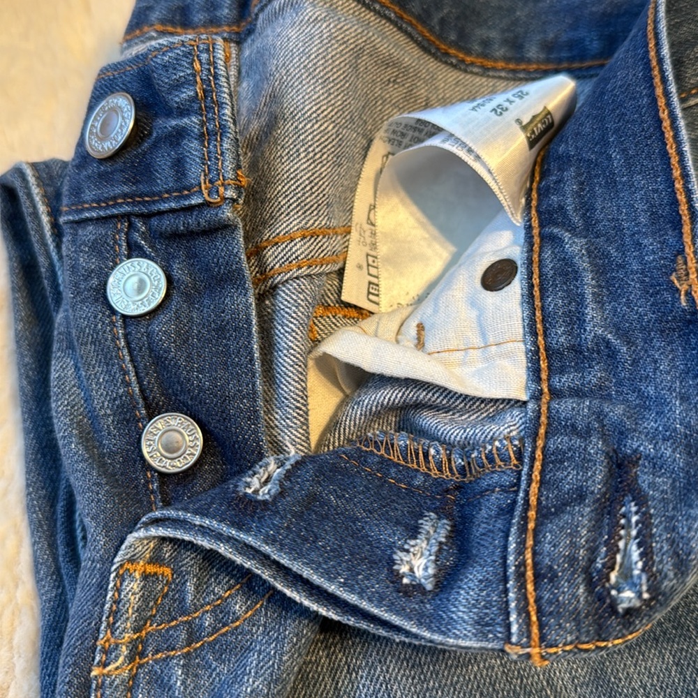 Vintage 501 25x32. Button fly. Distressed areas. Leather Levi’s branding label.